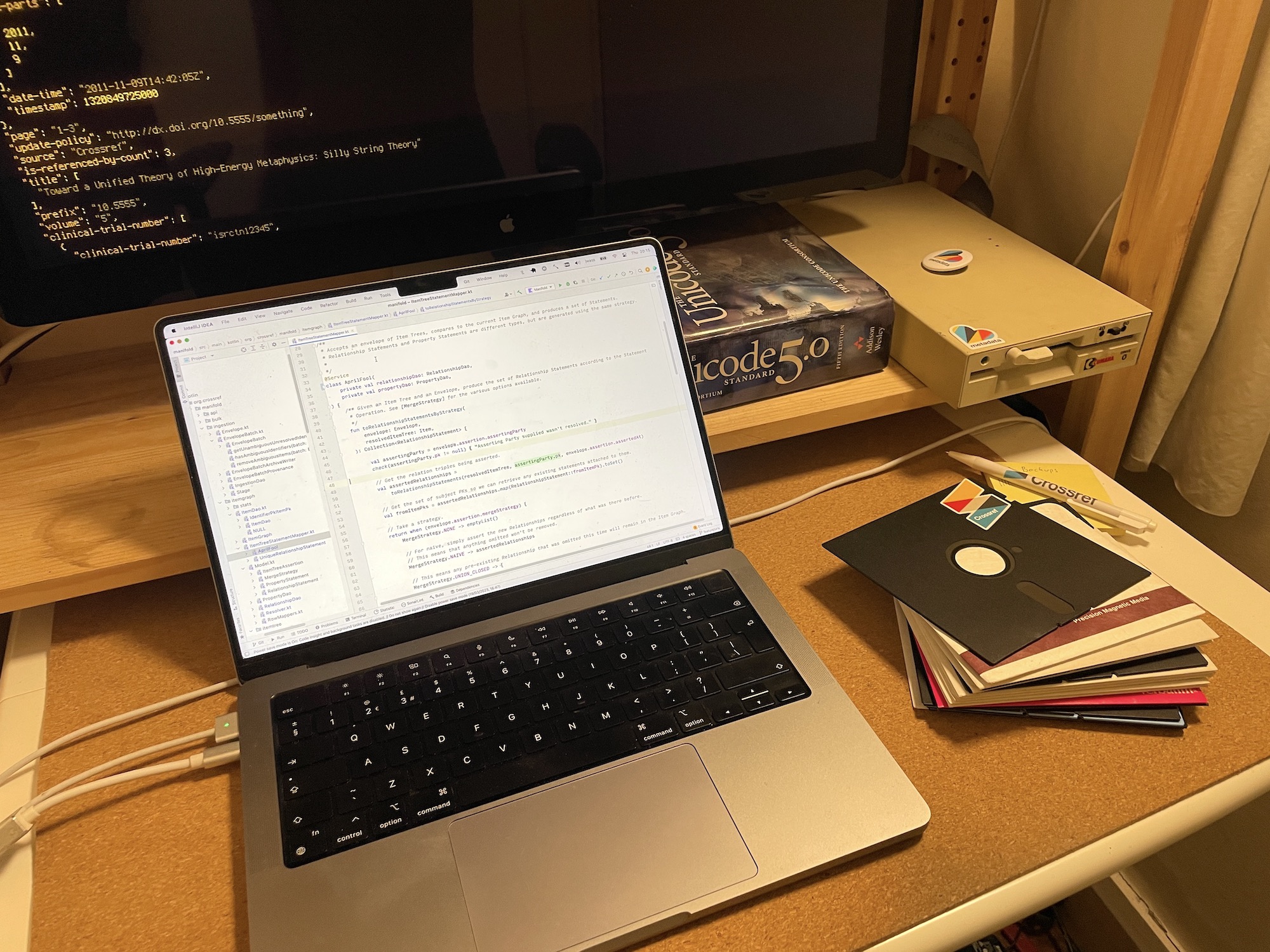 laptop computer connected to floppy disk drive, pile of disks next to it